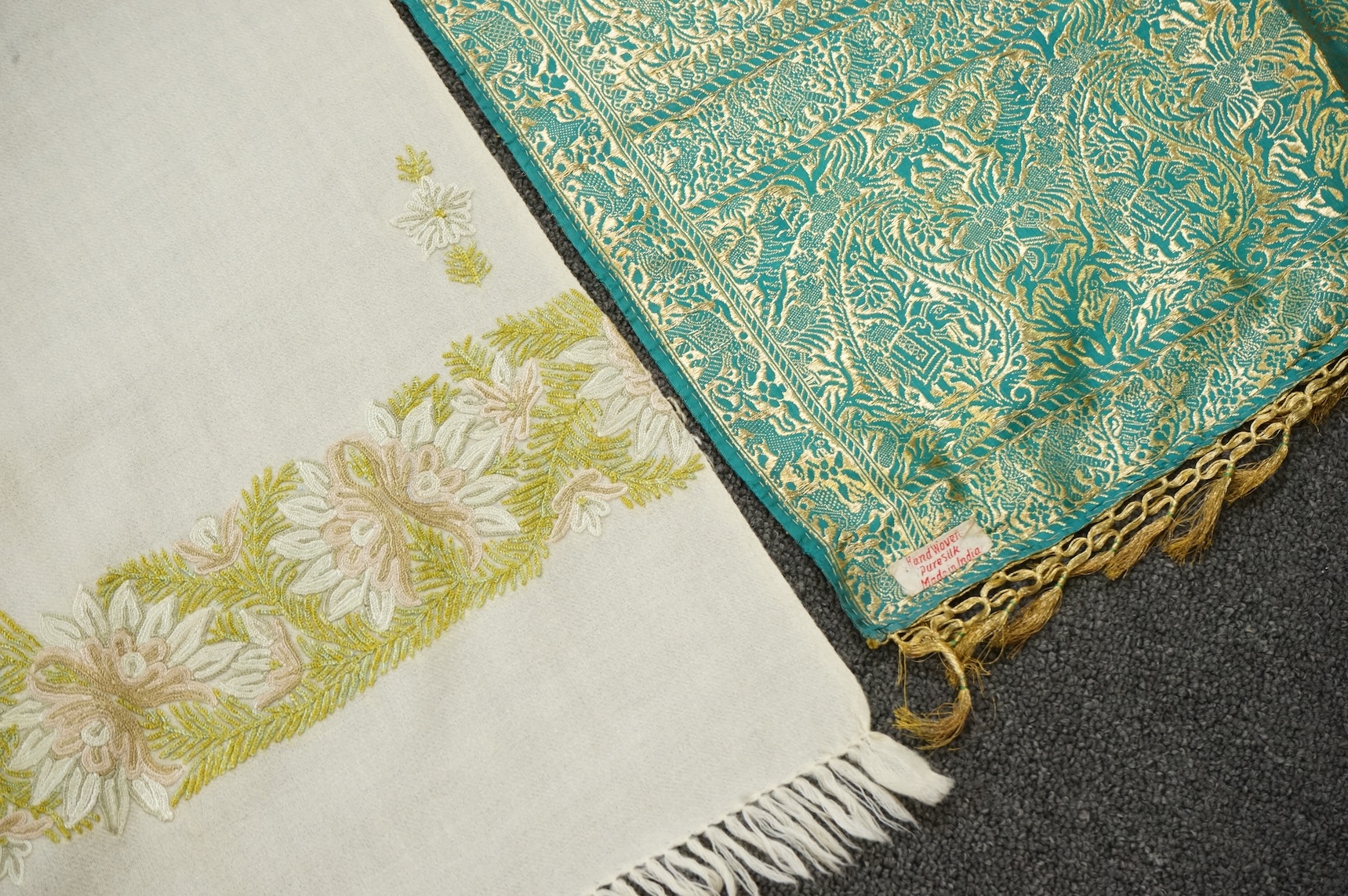 An Indian green and gold silk hand woven brocade stole, a cream pashmina embroidered stole and a similar finely woven and embroidered lilac stole (3). Brocade stole 38cm x 180cm., Condition - light stain to finely woven